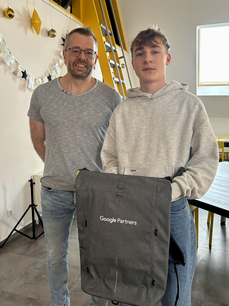 Google Partner Status für C3: Andreas Bäuml erhält Anerkennung von Google Andreas Bäuml (rechts) und Christian Walter (links) stehen in der Lounge der Werbeagentur. Andreas hält einen Google Partners-Rucksack in der Hand – ein Geschenk zur Anerkennung des neuen Google Partner Status der Agentur.