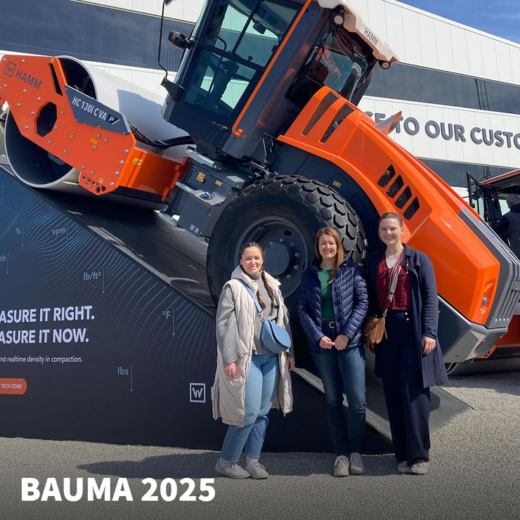 C3 Delegation auf der bauma 2025 in München Drei Mitarbeiterinnen der C3 marketing agentur stehen vor einer orangefarbenen HAMM-Baumaschine auf der bauma 2025 in München.