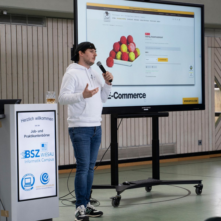 Vortrag bei der Jobbörse am Informatik Campus (BSZ Wiesau) Ein Mitarbeiter der C3 marketing agentur hält einen Vortrag bei der Job- und Praktikantenbörse des BSZ Wiesau. Im Hintergrund ist eine Präsentation zu einem E-Commerce-Projekt zu sehen.